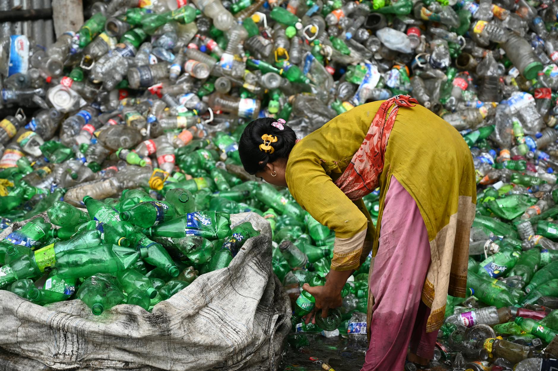 Kobieta segreguje plastikowe butelki do recyklingu w Bangladeszu