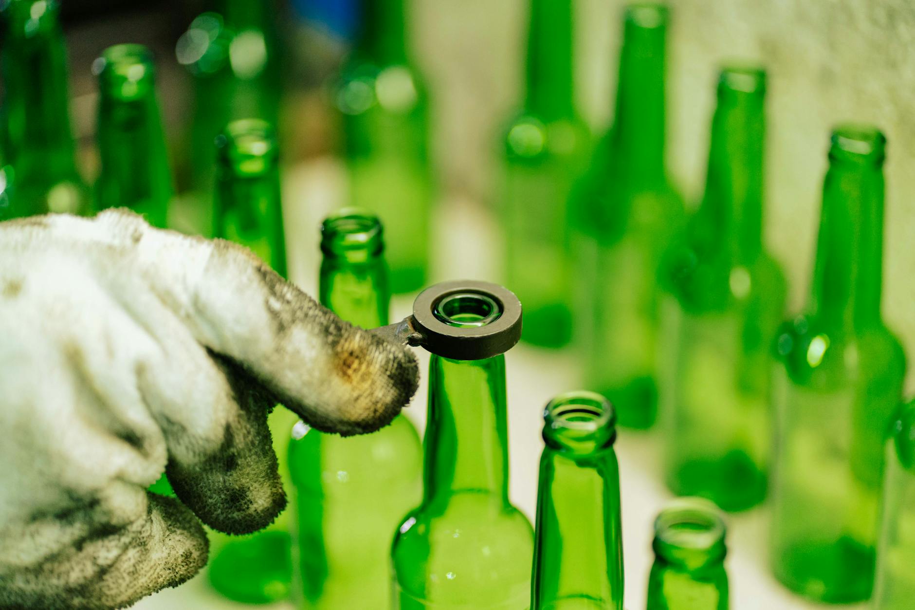 Pracownik sortuje zielone butelki szklane w zakładzie recyklingu