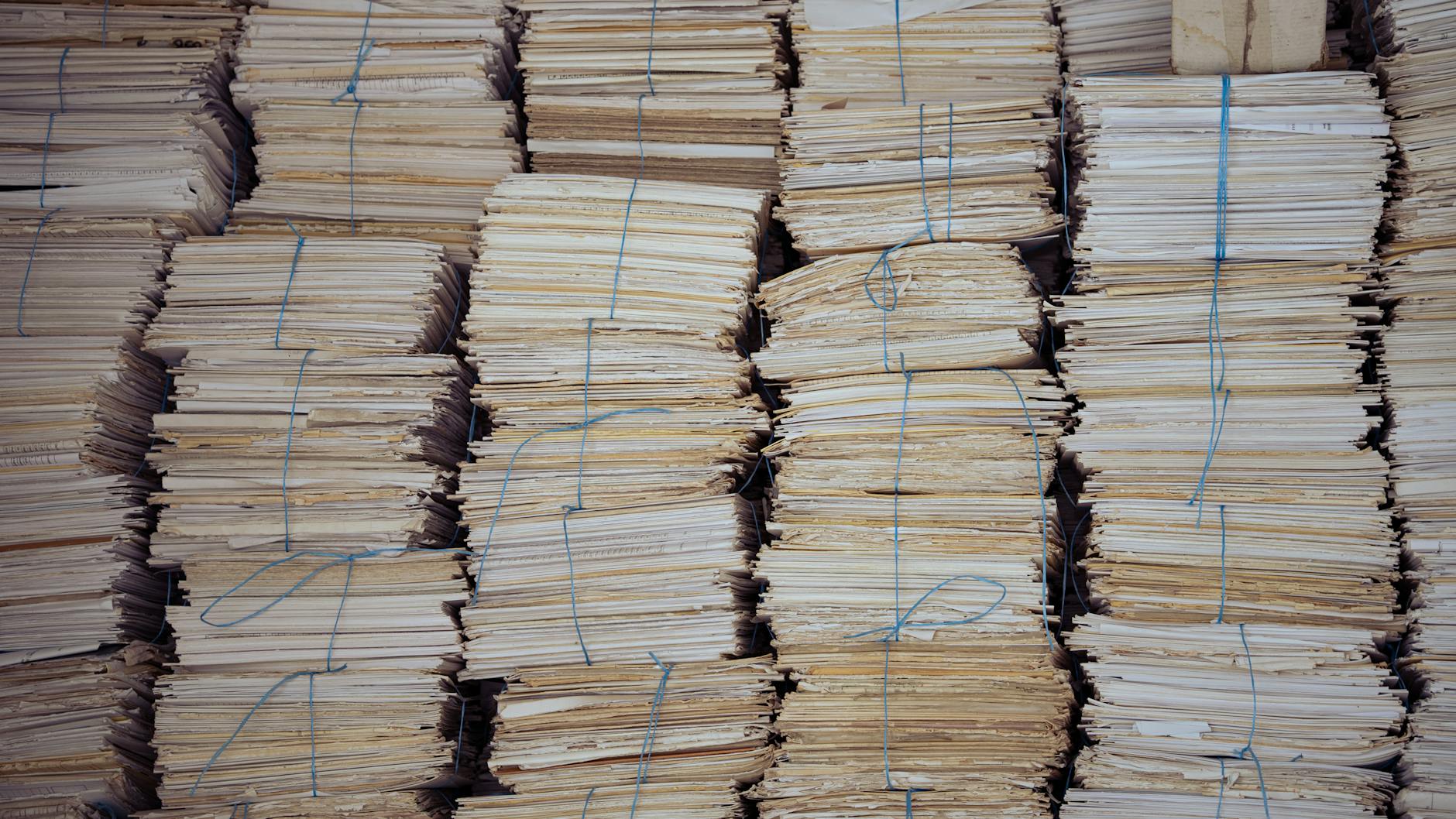 Wysokie sterty posegregowanych i zbindowanych stosów papieru