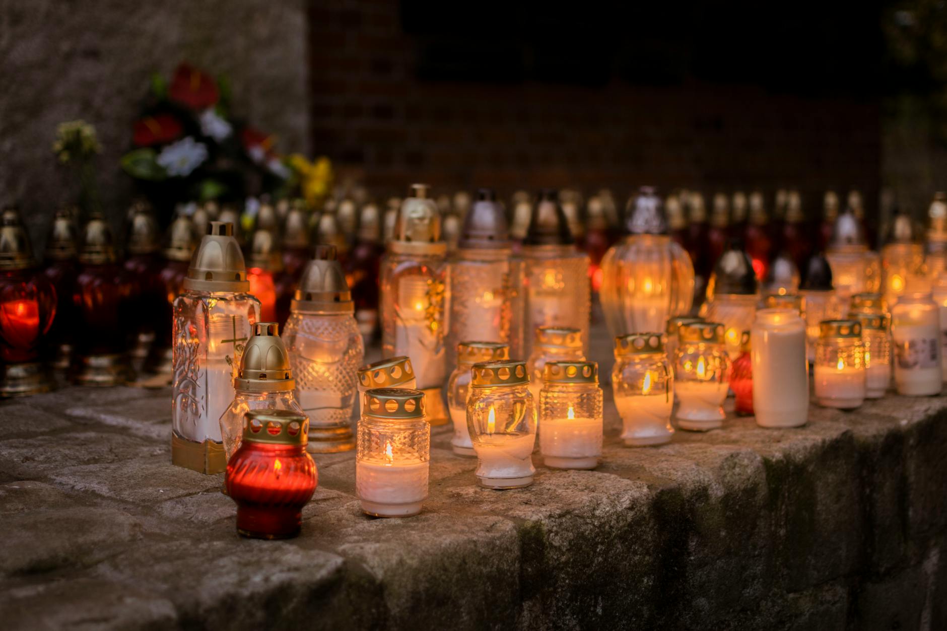 Zapalone znicze na cmentarzu w dzień Wszystkich Świętych
