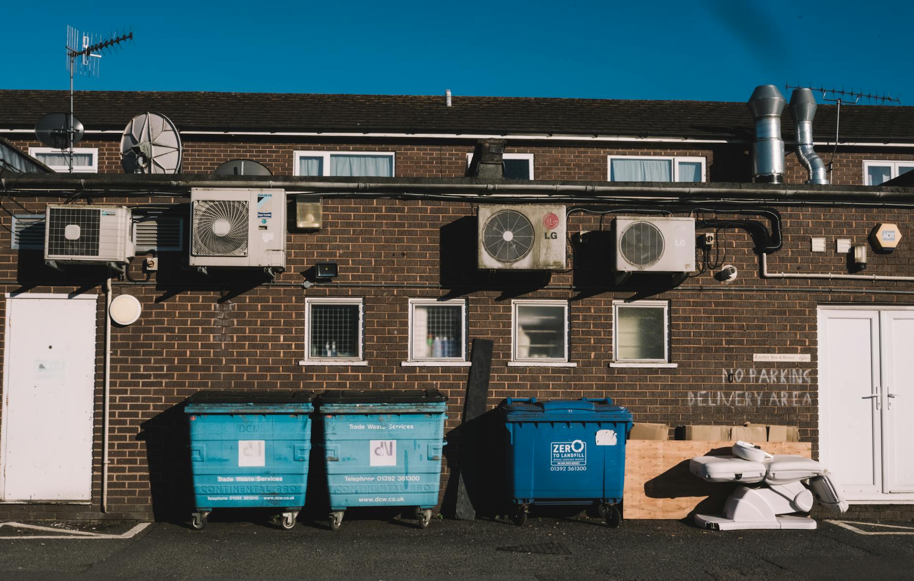 Alleyja przy budynku z cegły z kontenerami na odpady do recyklingu