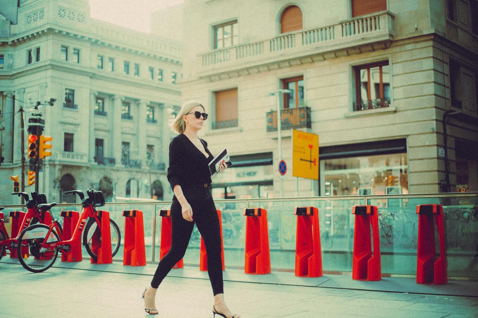 Elegancka kobieta w czerni idzie obok stojaka z rowerami w europejskim mieście