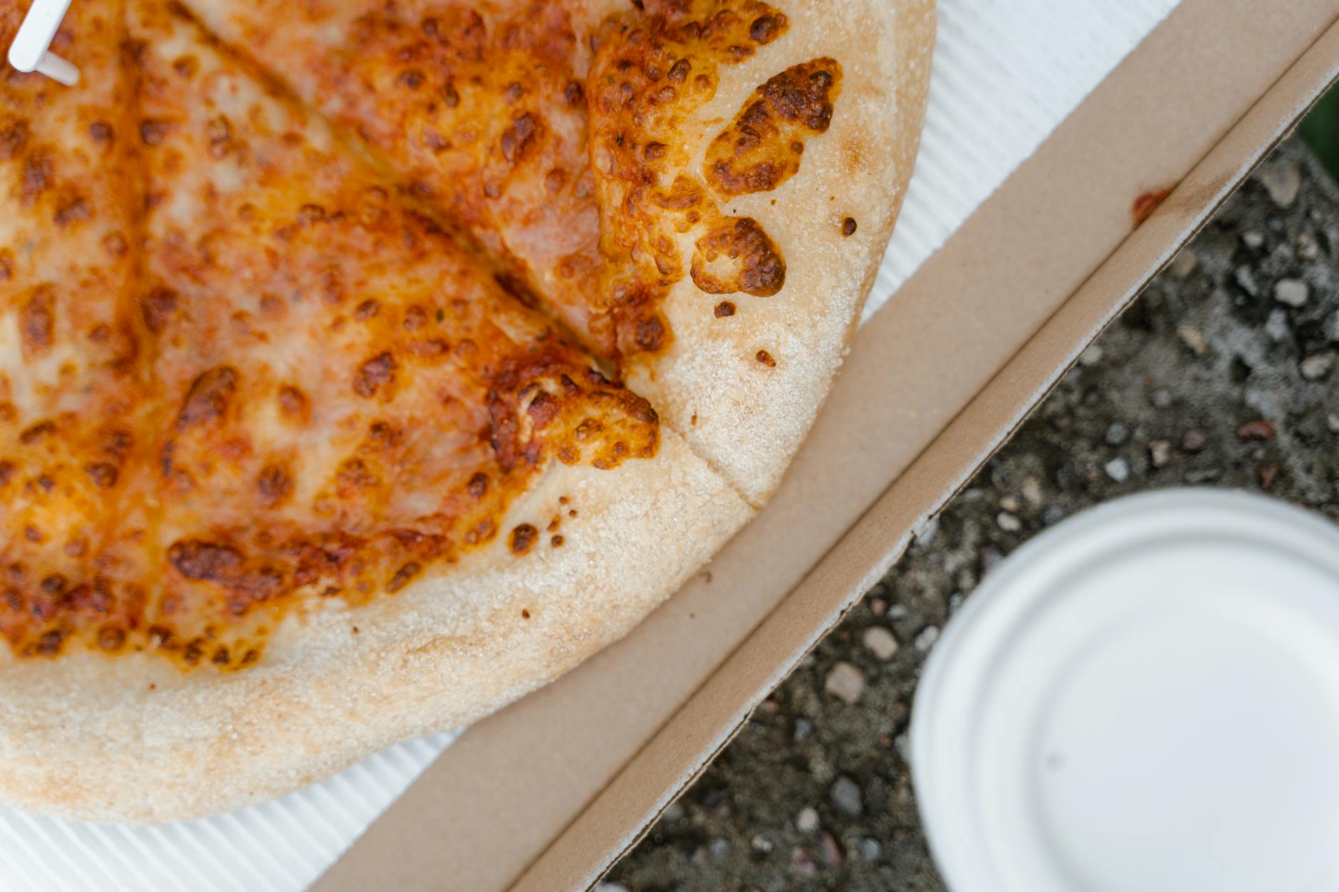 Kartonowe pudełko z kawałkiem serowej pizzy z bliska