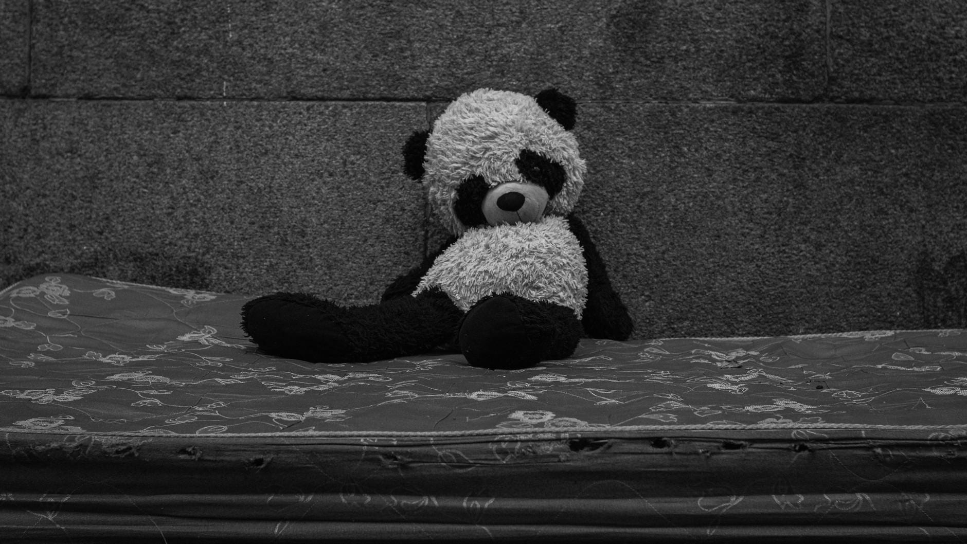 Pluszowy miś panda siedzący samotnie na starym, zużytym materacu