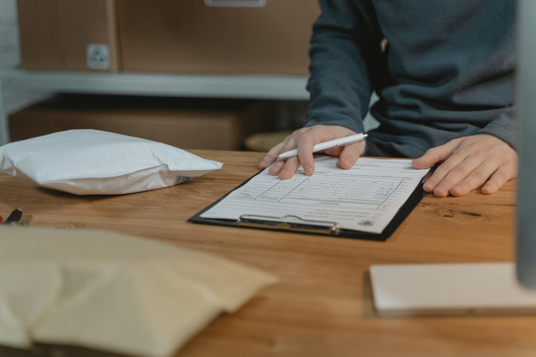 Pracownik w biurze wypełnia formularz przy kartonowych paczkach