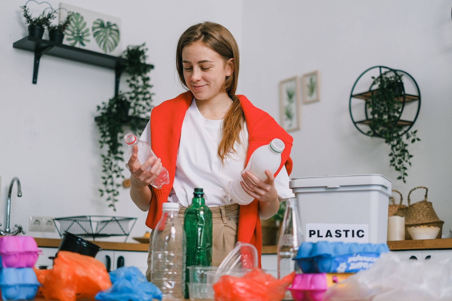 Kobieta w kuchni segreguje plastikowe butelki do recyklingu