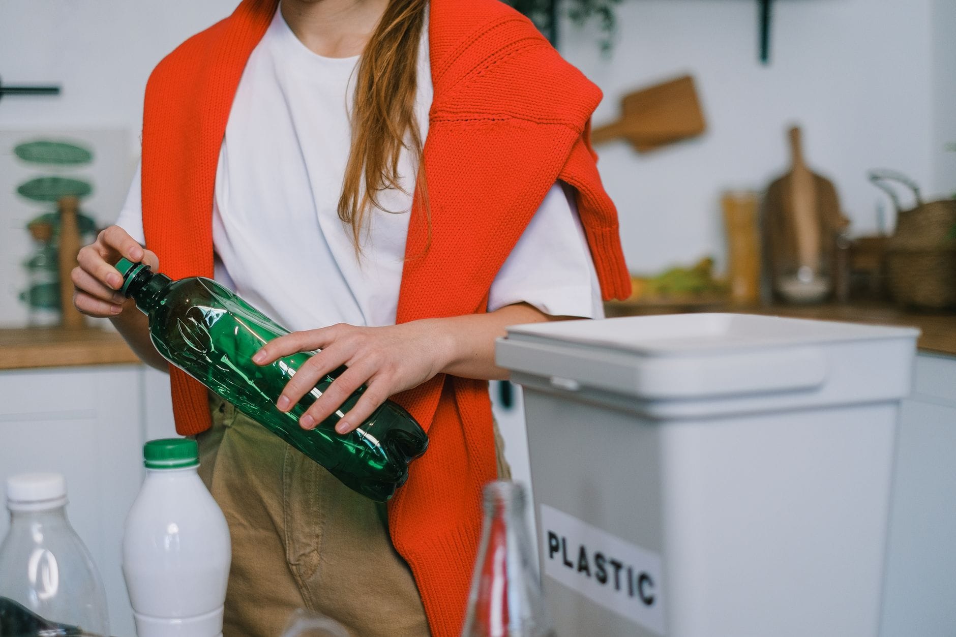 Kobieta w kuchni zgniata plastikową butelkę przed recyklingiem