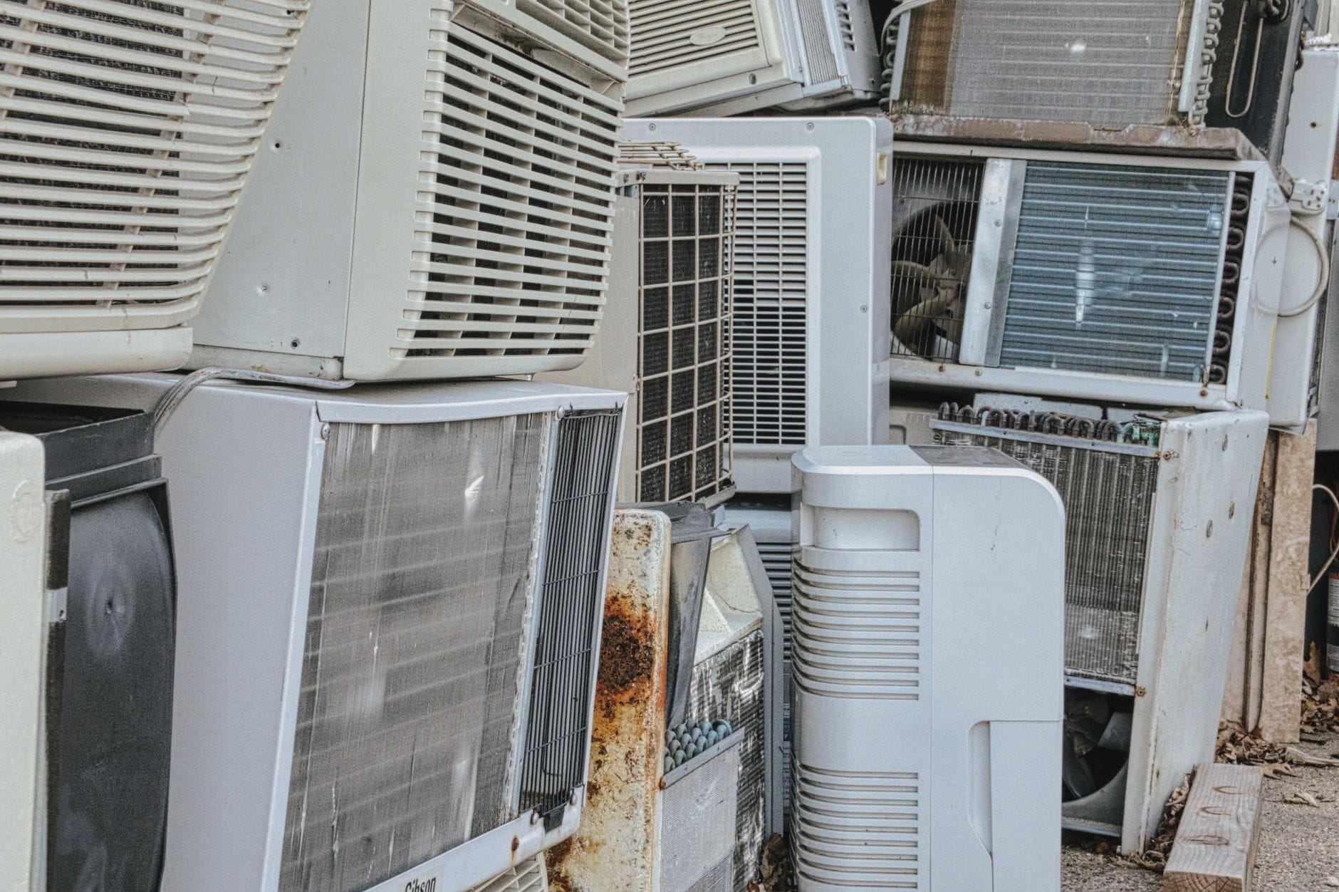 Stare uszkodzone klimatyzatory złożone w stertę na zewnątrz