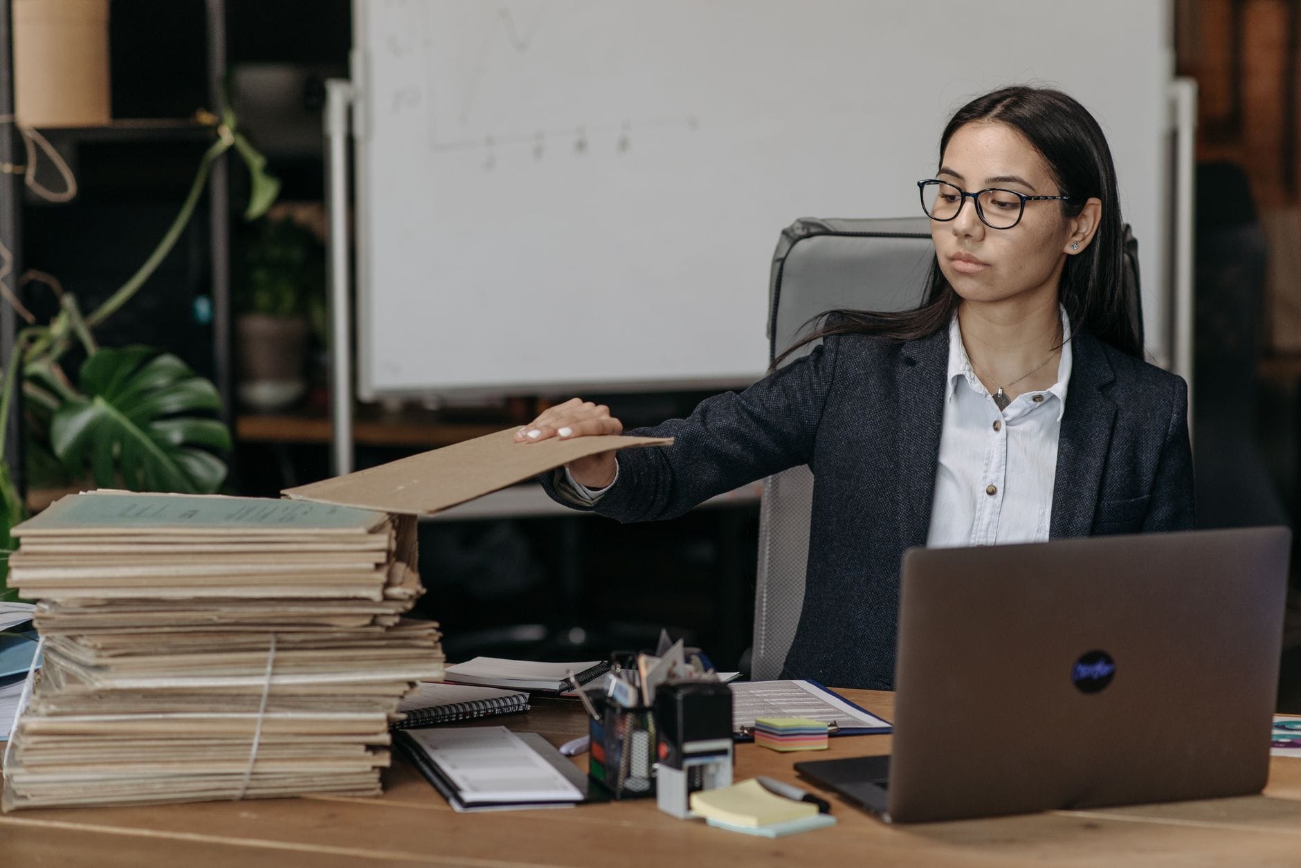 Bizneswoman przy biurku porządkuje dokumenty obok laptopa